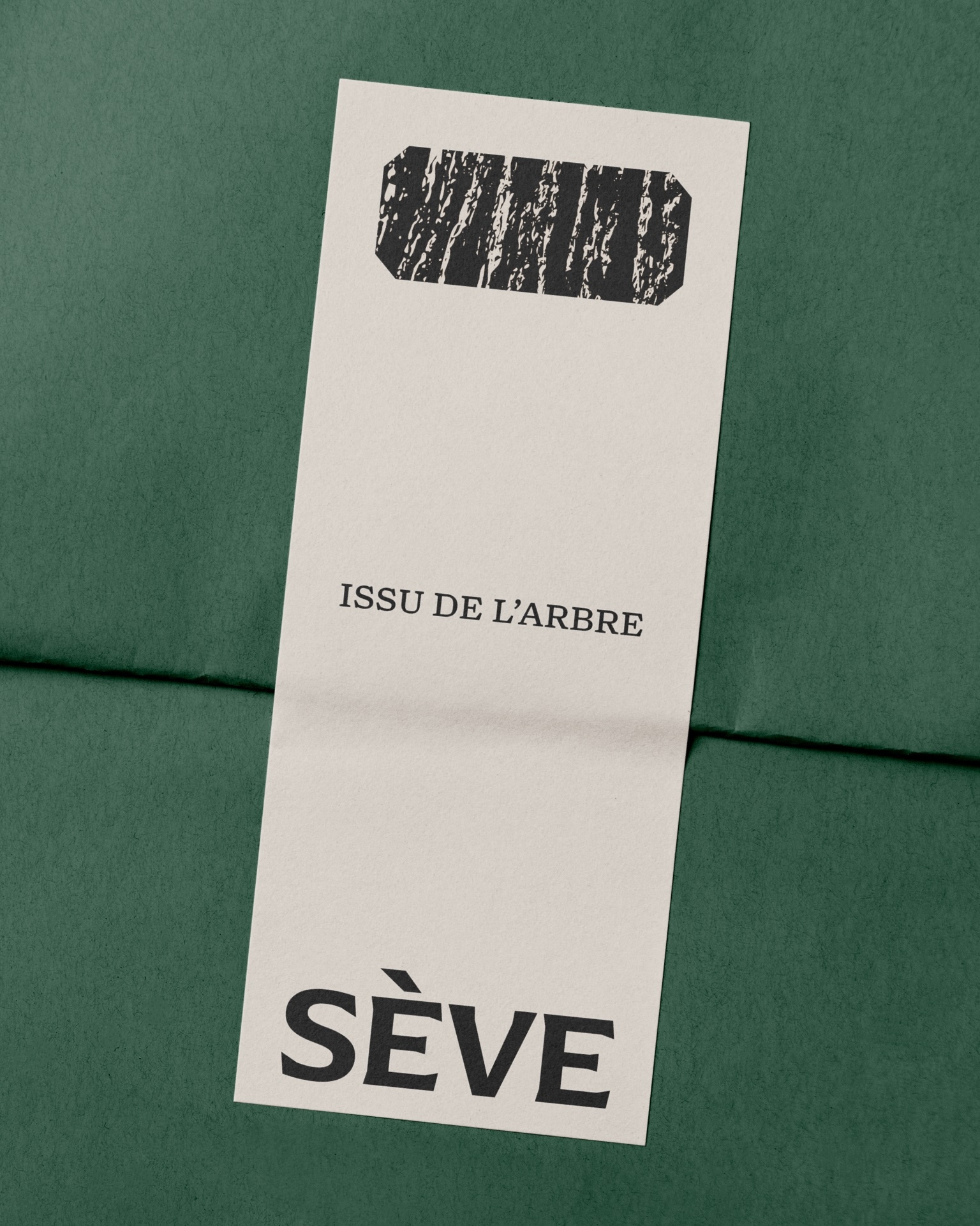 Rectangular off-white paper tag with black typography and SÈVE branding placed over textured dark green packaging paper.