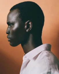 Profile portrait of a Black man wearing a white collared shirt against a warm neutral backdrop for Massimo Dutti