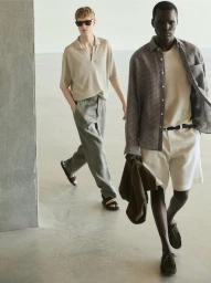 Two male models walking in a minimalist interior space wearing casual summer menswear collections