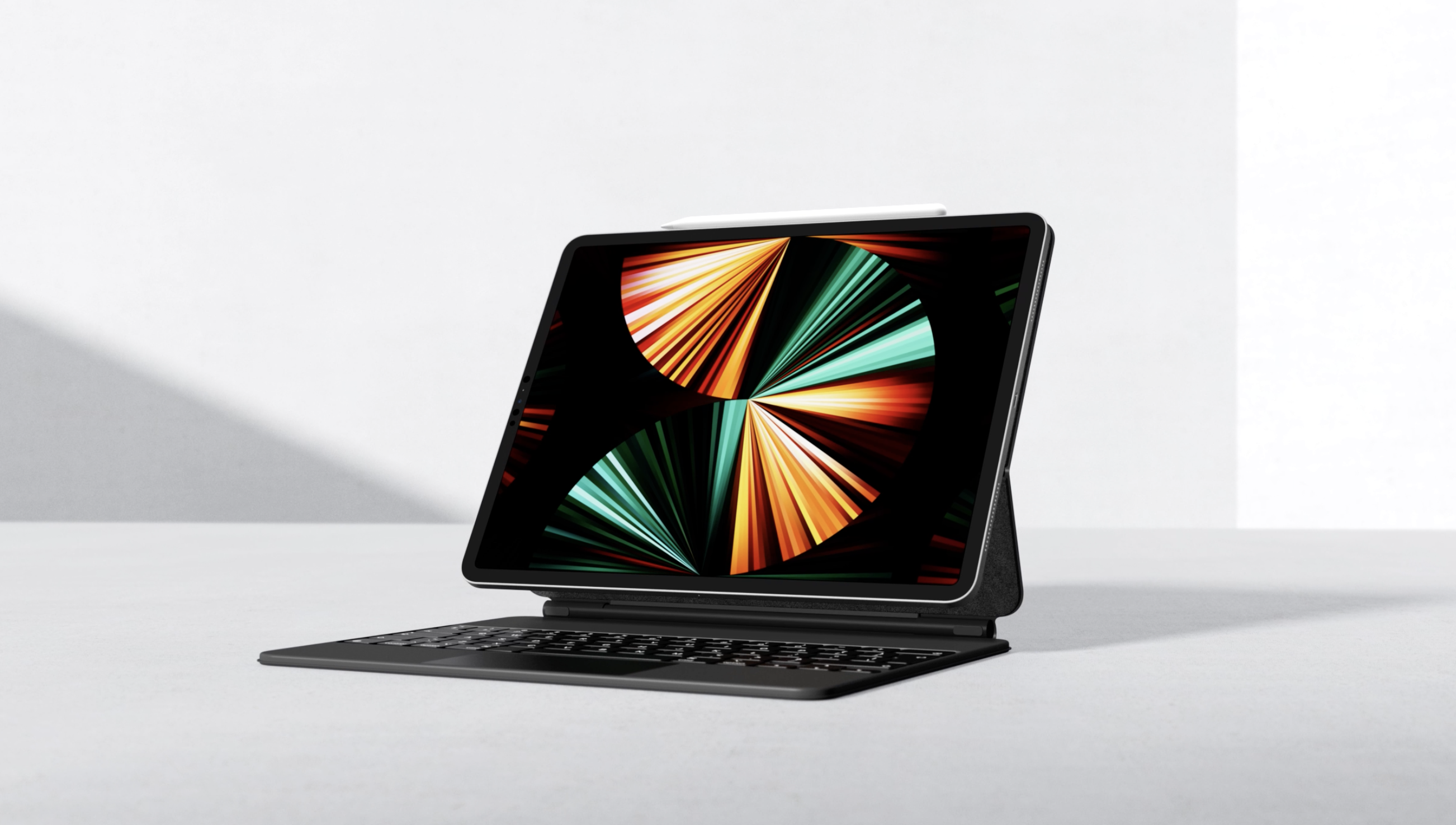 Black tablet computer with keyboard attachment on white surface showing a colorful abstract digital display and a stylus pen on top.