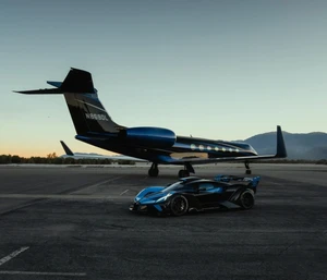 Bugatti Bolide sports car in black and blue parked on an airfield tarmac in front of a matching private jet at dusk.