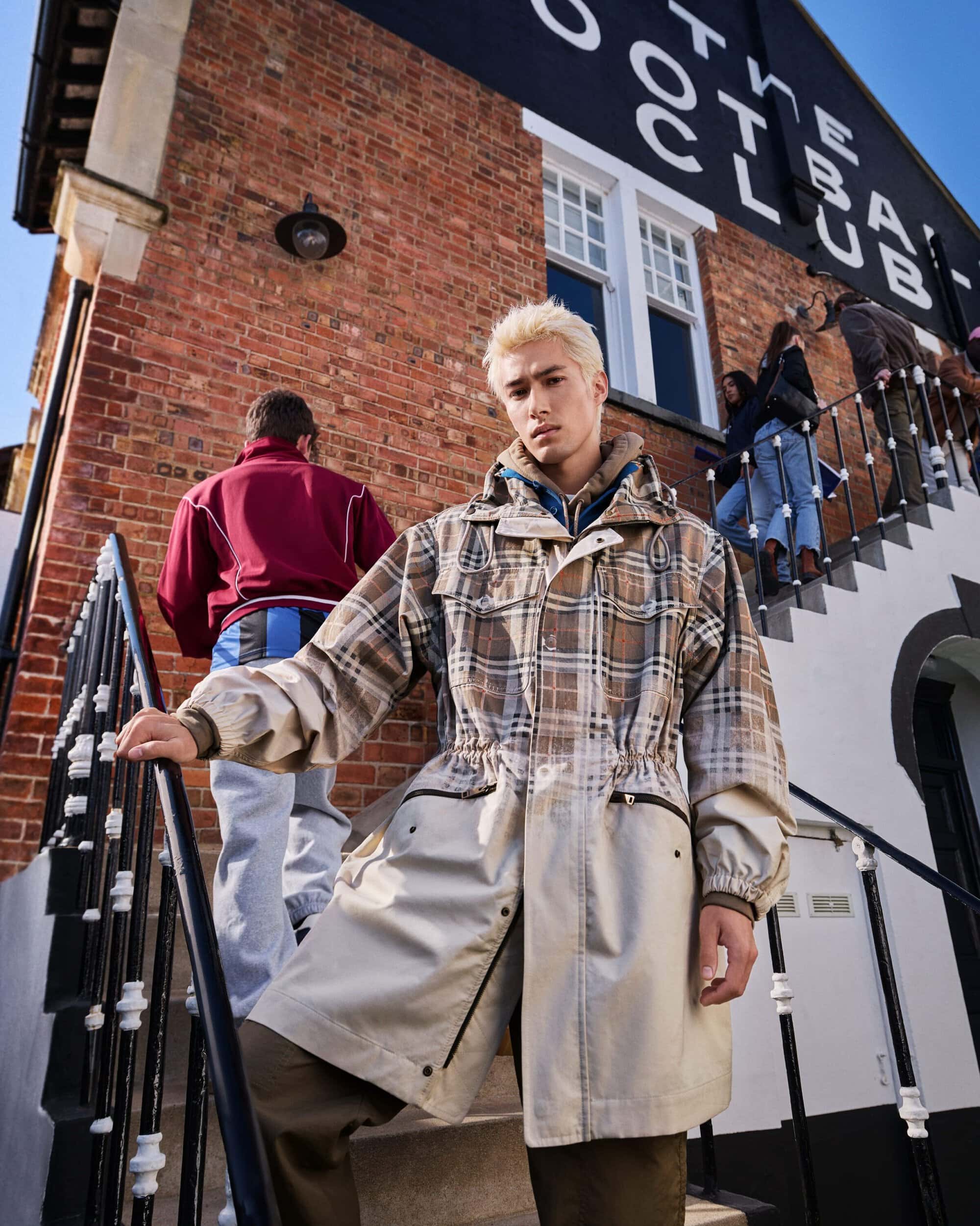 Model Bright posing on outdoor brick steps wearing a beige and brown plaid hooded drawstring parka from Burberry.