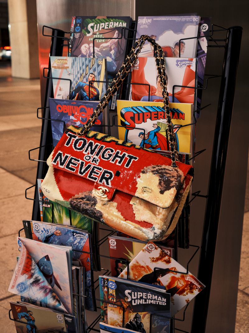 Chanel embroidered flap bag with Tonight or Never text hanging on a wire magazine rack filled with comic books.