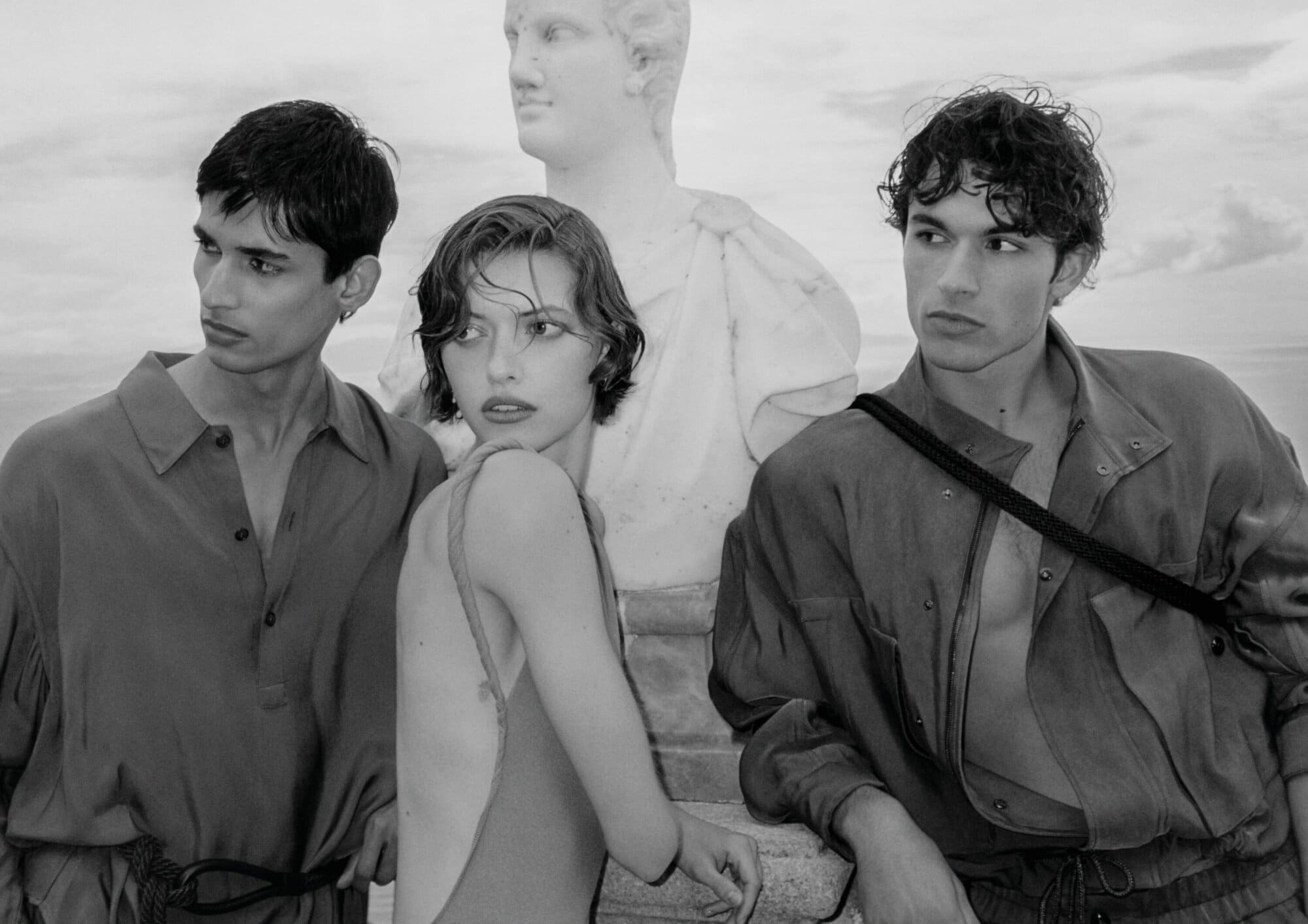Black and white portrait of three models posing outdoors near a classical marble bust for Giorgio Armani.