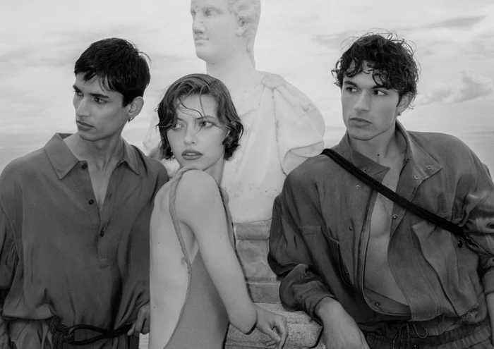 Black and white portrait of three models posing outdoors near a classical marble bust for Giorgio Armani.