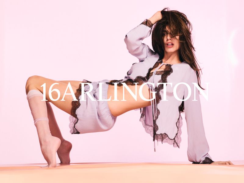 Cala Moragas poses in a lilac silk set with black lace trim against a pink studio background for 16Arlington.