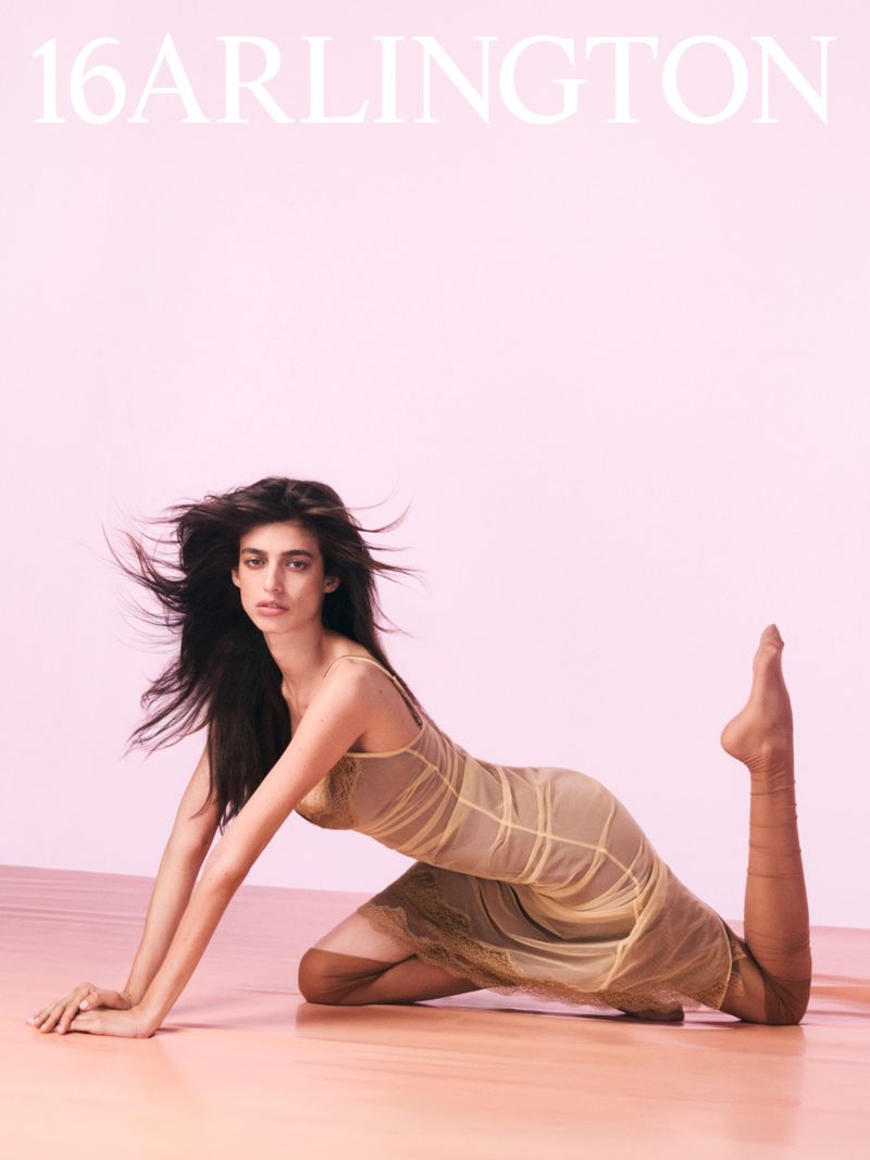 Brunette woman in a yellow mesh dress poses on a pink background, fashion photography, studio lighting. Full-body shot for 16 Arlington fashion brand.