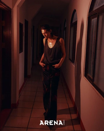 Model Taemin Park standing in a dimly lit hallway wearing a dark tank top and dark patterned trousers.