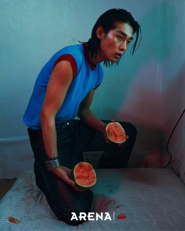 Model Taemin Park kneels on a mattress holding halved watermelons in a blue sleeveless top for Arena Homme Korea.