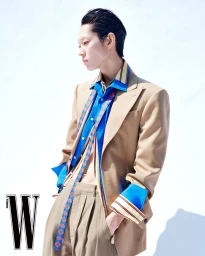 Model Minki Kwon in a layered beige blazer, open blue button-down shirt, and pleated trousers against a white background for W Korea.