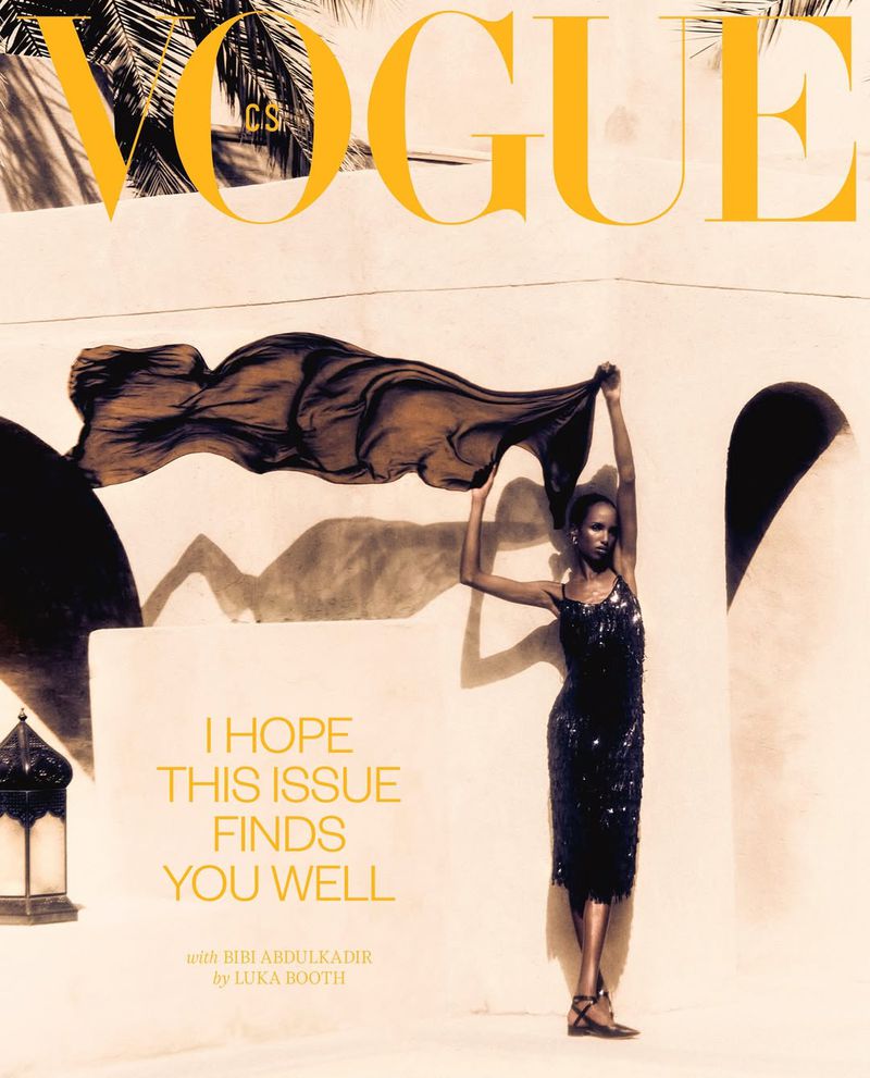 Vogue magazine cover featuring a slender woman in a black sequined dress holding a dark scarf in front of a light-colored wall.