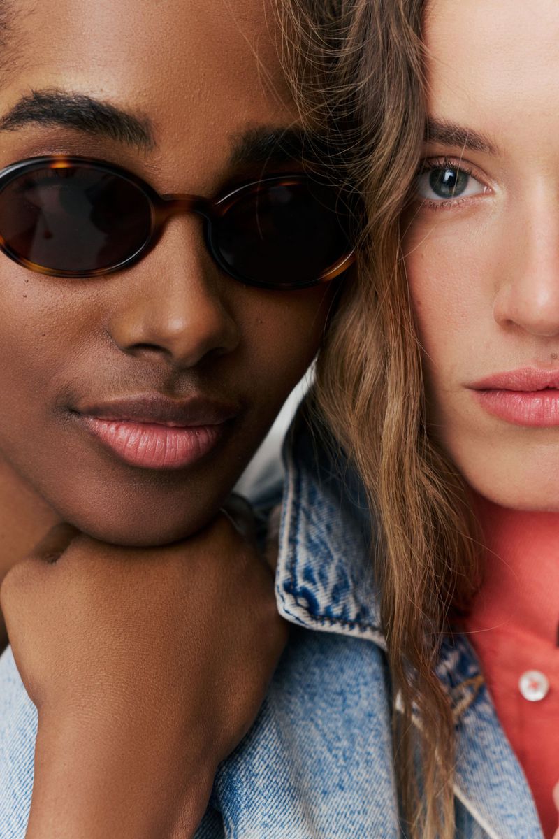 Close-up of model Tami Williams in dark oval sunglasses and denim beside model Altyn Isabella for Tuckernuck.