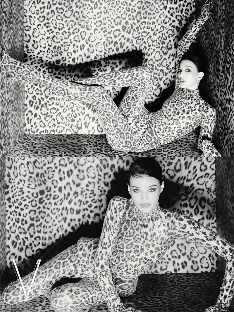 Model wearing a full-body leopard print catsuit posing inside a matching leopard print enclosure in black and white.