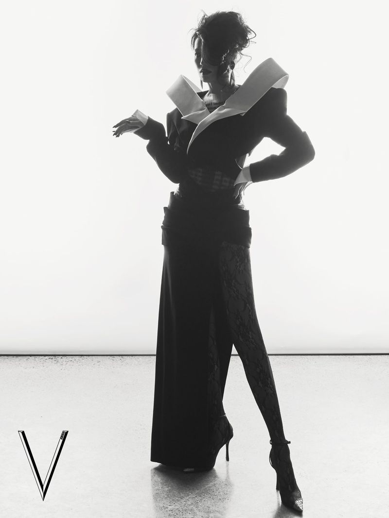 Model in architectural structured dark jacket and long skirt against a bright white background