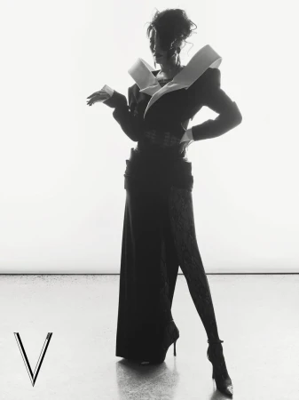 Model in architectural structured dark jacket and long skirt against a bright white background