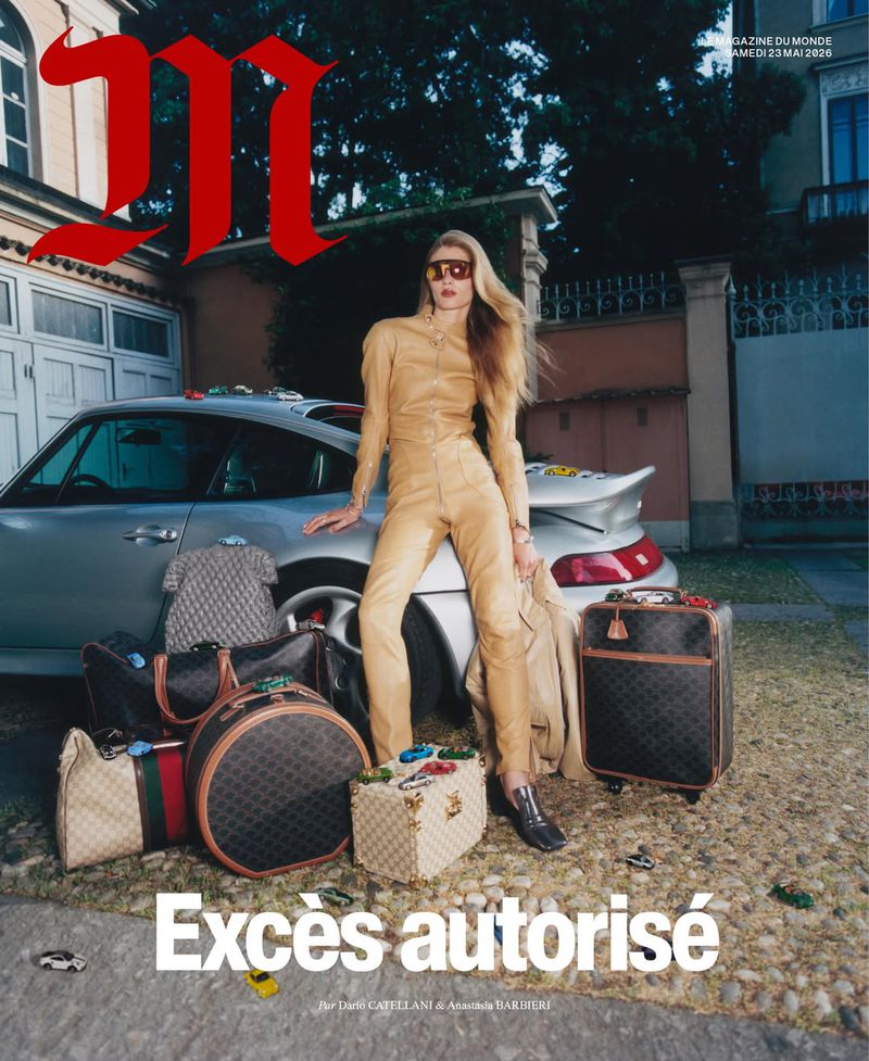 Model wearing a tan leather jumpsuit and sunglasses leaning against a silver sports car surrounded by monogram luggage.