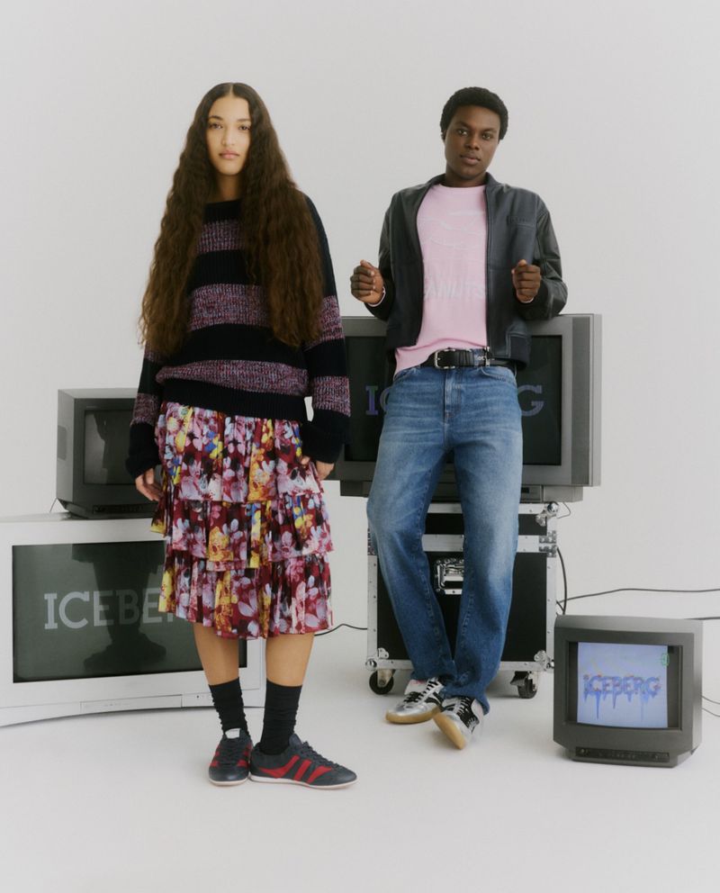 Two models posing in Iceberg apparel beside vintage CRT television monitors in a bright studio setting.