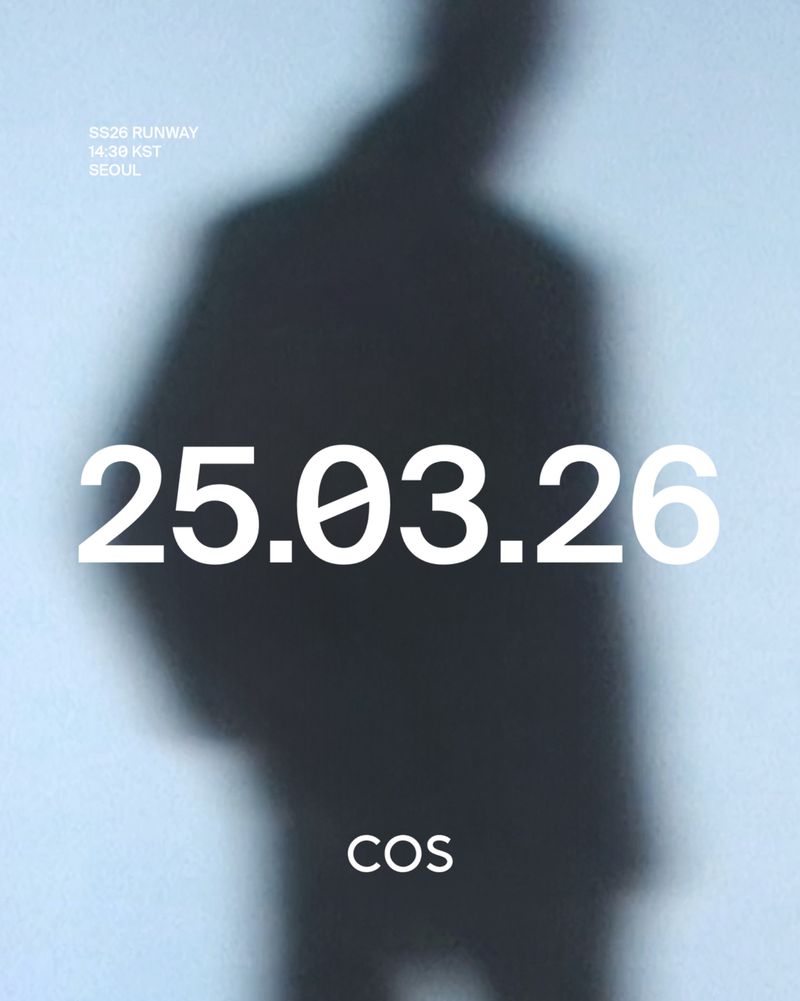 Blurred dark silhouette of a figure against a pale blue background with white typography for the COS S/S 26 runway show.