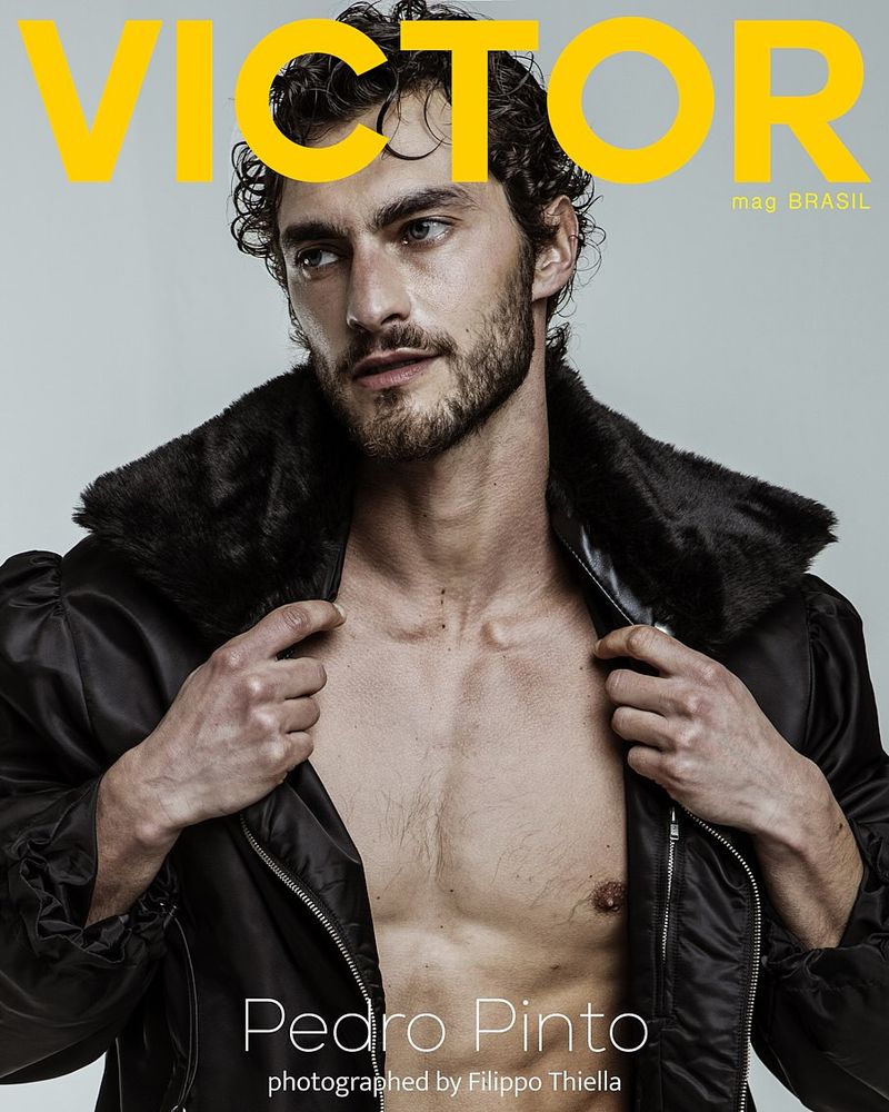 Model Pedro Pinto wearing an open black jacket with a fur collar against a light grey background for Victor Magazine Brasil.