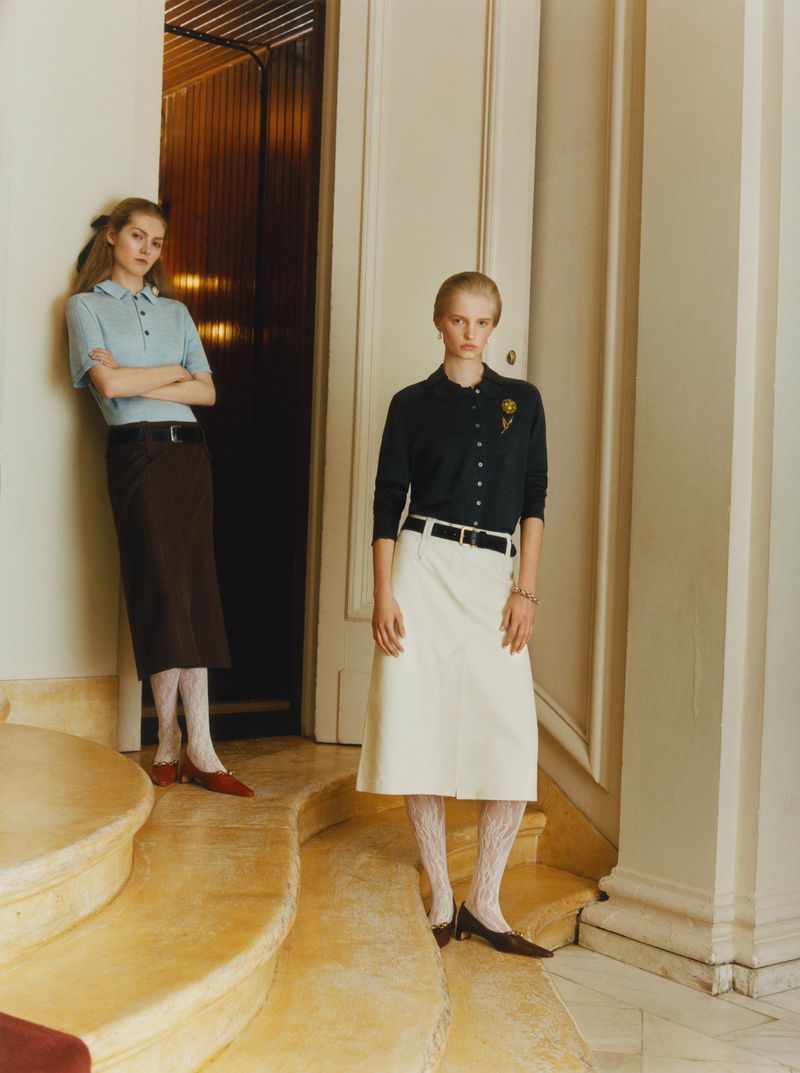 Two female models posing on curved stone stairs in an upscale interior for a WSJ fashion editorial shoot.