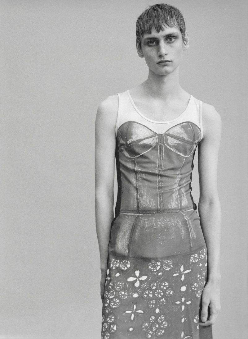 Monochrome studio portrait of a model with short cropped hair wearing a graphic trompe l'oeil corset print dress.