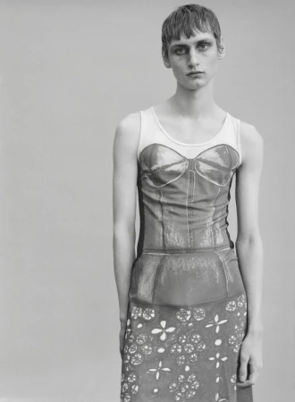Monochrome studio portrait of a model with short cropped hair wearing a graphic trompe l'oeil corset print dress.