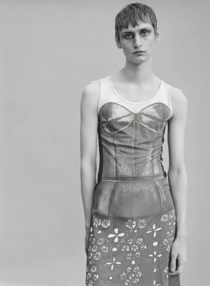 Monochrome studio portrait of a model with short cropped hair wearing a graphic trompe l'oeil corset print dress.