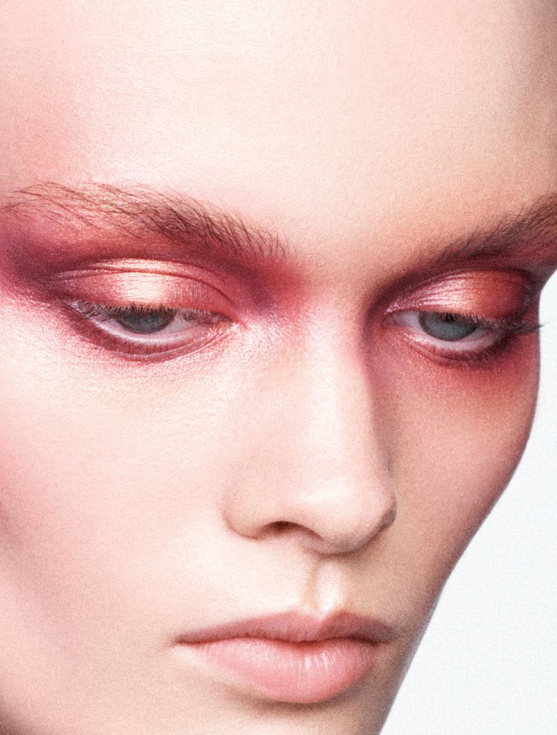 Close-up beauty portrait of a model featuring vibrant pink and rose shimmer eyeshadow blended around both eyes and across the nose bridge.