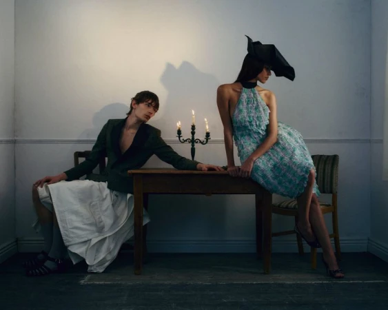 Two models posing near a wooden table with a candelabra in a room for Yung Magazine editorial