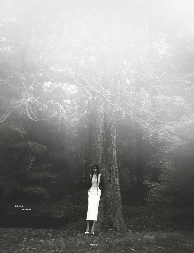 Model Ashley Radjarame standing against a large tree in a misty forest for Numero Netherlands Soft Remains
