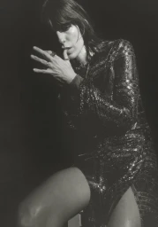 Monochrome portrait of Lou Doillon wearing a glittering sequin dress against a black background.