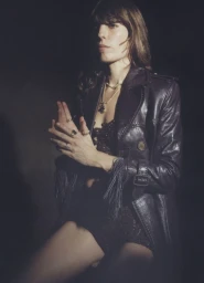 Lou Doillon wearing a dark fringed leather jacket and gold necklaces in a moody low-key studio portrait for Purple Magazine.