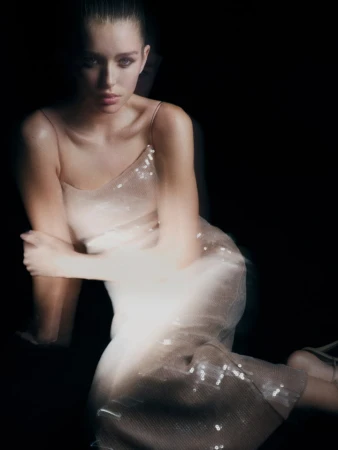 Model in a sequined dress sitting against a dark background for Witchery After Hours