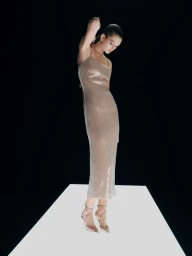 Model wearing a shimmering slip dress standing on a glowing platform against a black background