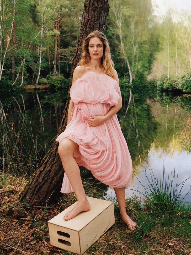 Model Natalia Vodianova wearing a pink tulle dress standing outdoors near a lake for Vogue France