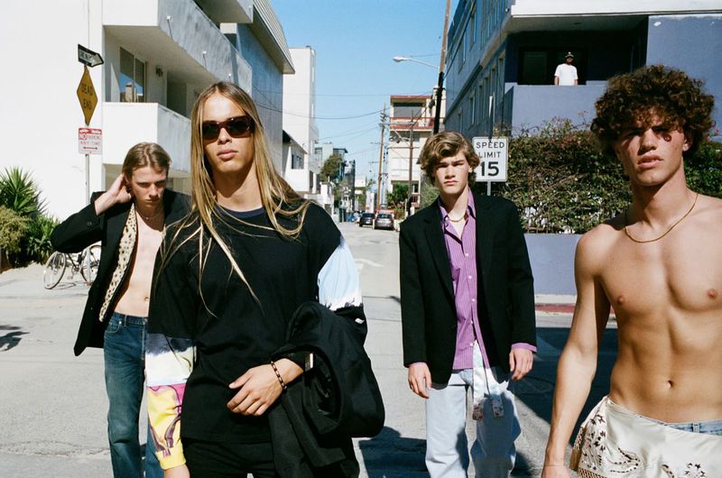 Four young male models walk down a sunny Venice Beach street in fashion styling for Arena Homme Plus.