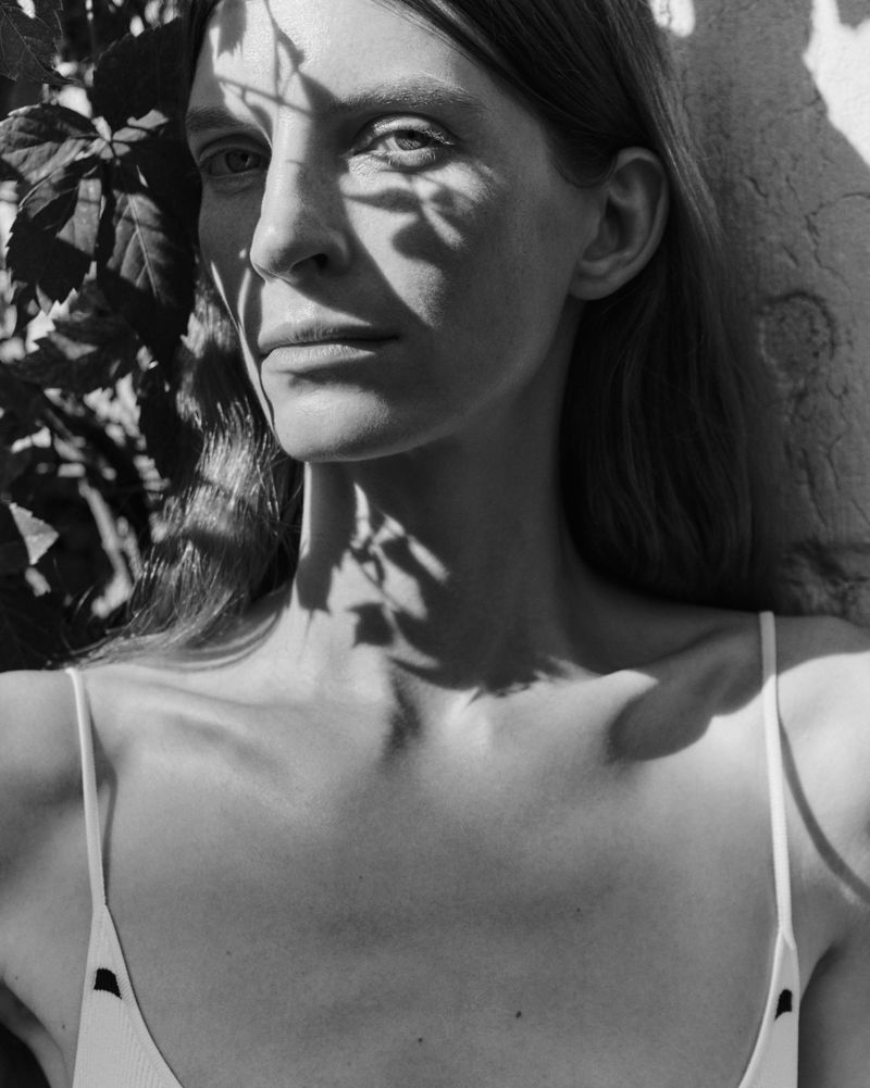 Black and white portrait of Luca Gajdus with leaf shadows across her face wearing a white spaghetti strap top.