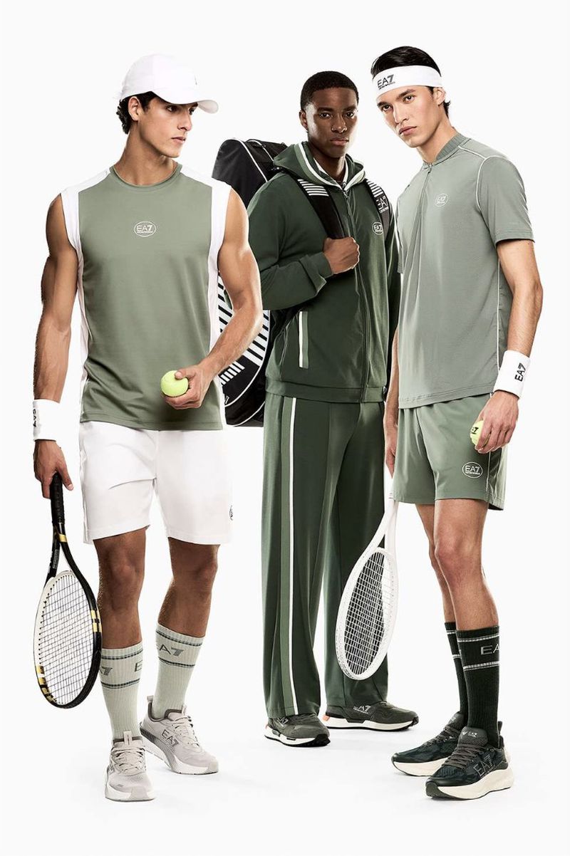 Three male models posing in green and white Emporio Armani tennis sportswear holding racquets against a white studio background.