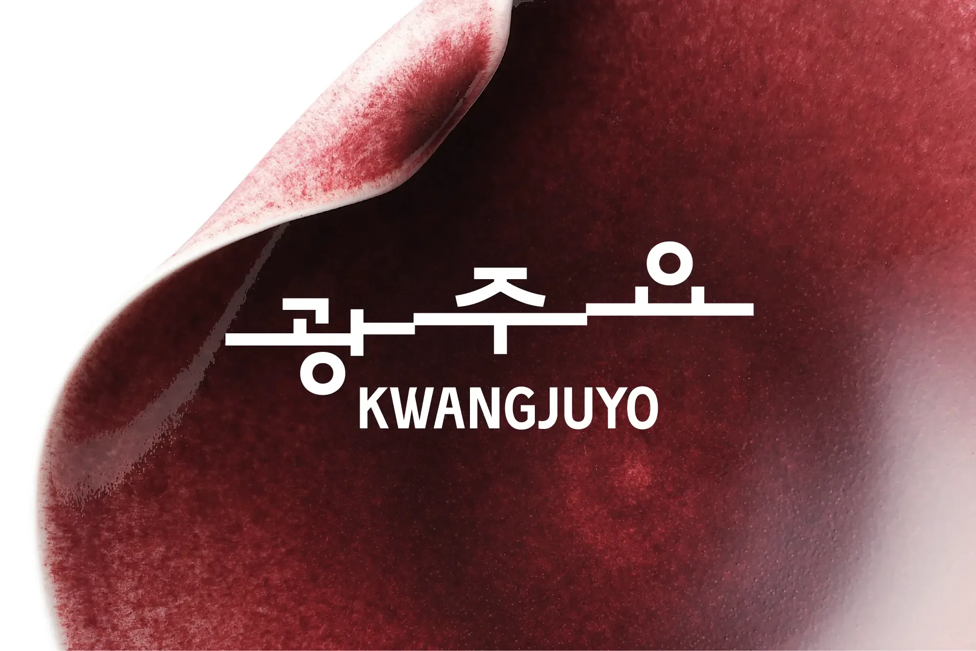 White Kwangjuyo logo in Hangul and English overlaid on a curved ceramic surface with a deep burgundy glaze.