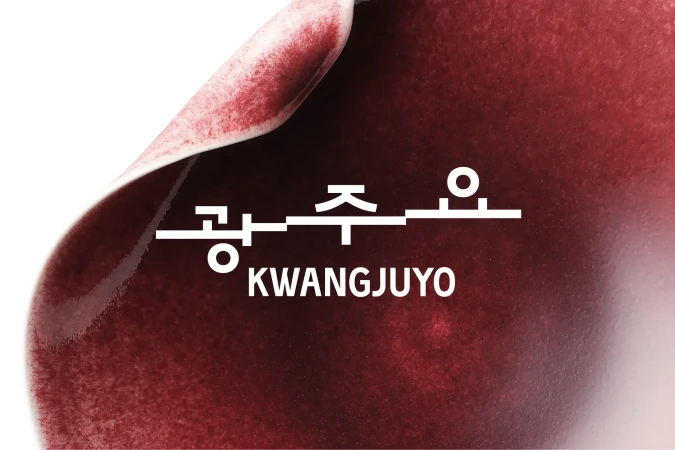 White Kwangjuyo logo in Hangul and English overlaid on a curved ceramic surface with a deep burgundy glaze.