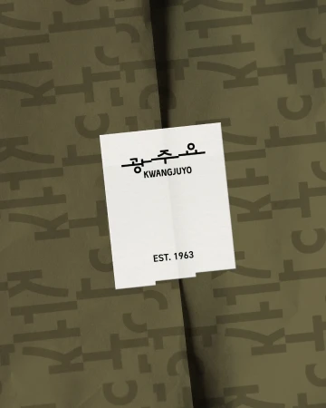 A white rectangular Kwangjuyo brand sticker sealing olive green wrapping paper printed with a Hangul typography pattern.