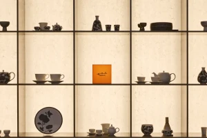 Ceramic teapots, cups, and vessels displayed on backlit grid shelving with an orange Kwangjuyo logo box in the center compartment.