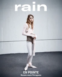 Model Roxane Marie poses in a ballet wrap top, brown bodysuit, and leggings against a concrete wall for Rain Magazine.
