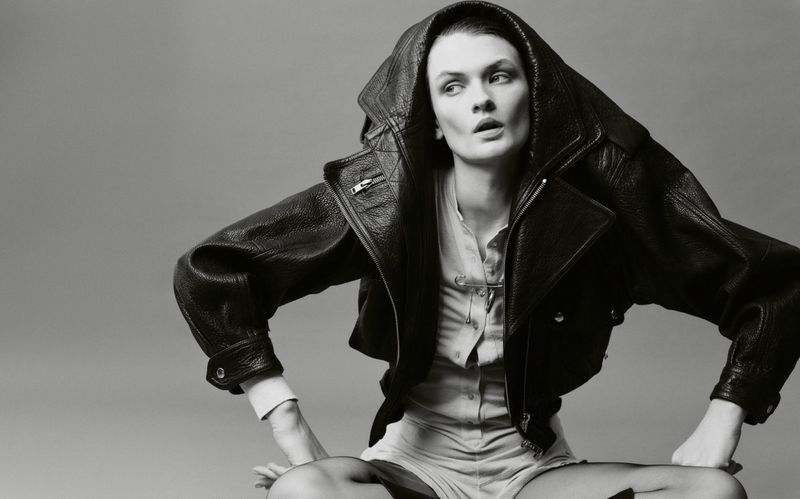 Model Lara Mullen posing in an oversized hooded black leather jacket against a studio backdrop.