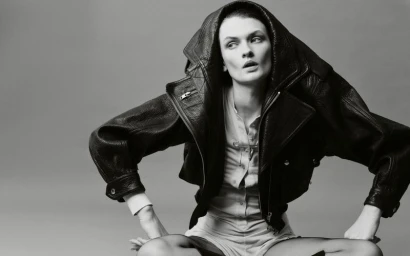 Model Lara Mullen posing in an oversized hooded black leather jacket against a studio backdrop.