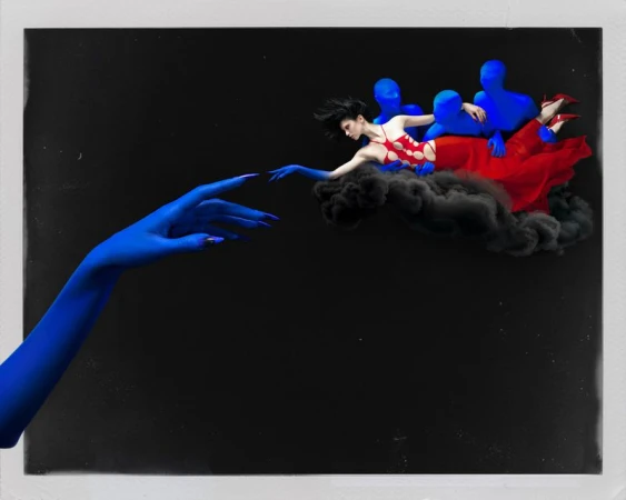 Surreal fashion editorial featuring a floating woman in a red cutout dress and reaching blue painted hands against a black background.
