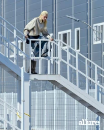 Model Minji Lee in a beige pullover and wide-leg trousers posing on a white metal outdoor staircase for Allure Korea.