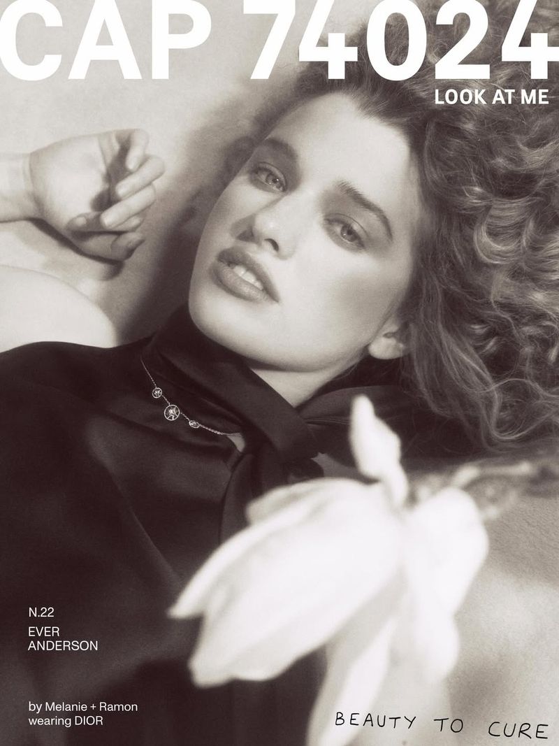 Black and white magazine cover featuring Ever Anderson reclining in a dark high-neck top holding a white flower.