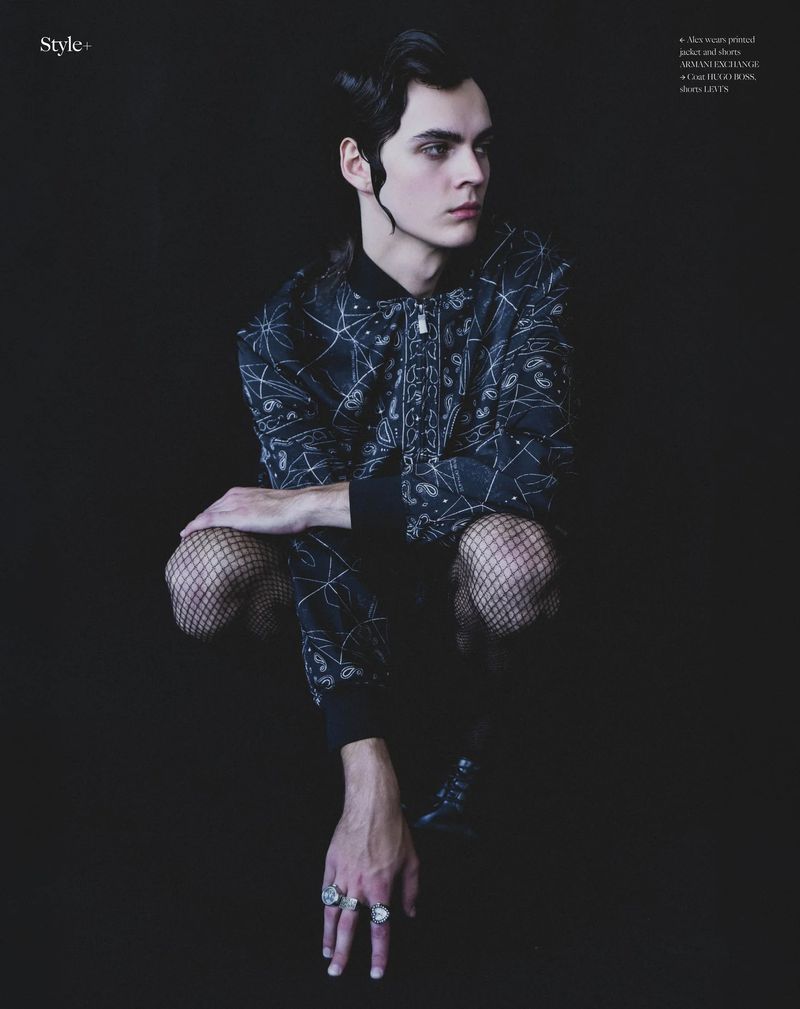 Model in patterned jacket and fishnet tights crouching against a dark seamless background for editorial