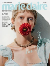 Model Anna Pavlova with a red dahlia flower held in her mouth wearing a gold beaded necklace on the cover of Marie Claire Italia.